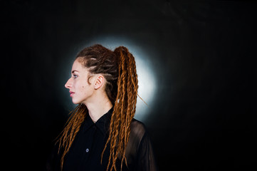 Studio shoot of girl in black with dreads at black background with nimbus.