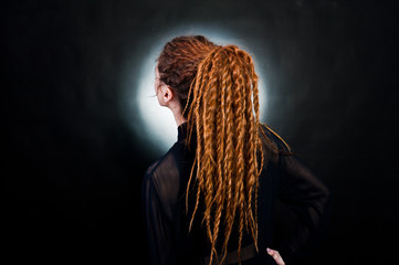 Studio shoot back of girl in black with dreads at black background with nimbus. - obrazy, fototapety, plakaty