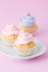 Cupcake decorated with pink and violet buttercream on pastel pink background. Sweet beautiful cake. Vertical banner, greeting card for birthday, wedding. Close up photography. Selective focus