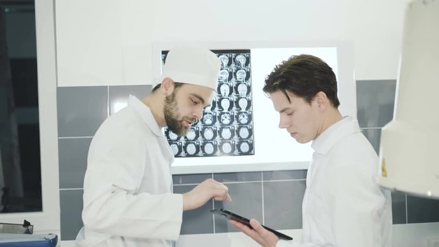 Two doctors advising at mri display in hospital room. 4K