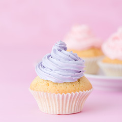 Cupcake decorated with pink and violet buttercream on pastel pink background. Sweet beautiful cake. Square banner, greeting card for birthday, wedding. Close up photography. Selective focus