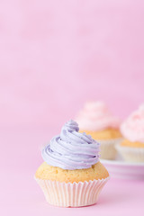 Cupcake decorated with pink and violet buttercream on pastel pink background. Sweet beautiful cake. Vertical banner, greeting card for birthday, wedding. Close up photography. Selective focus