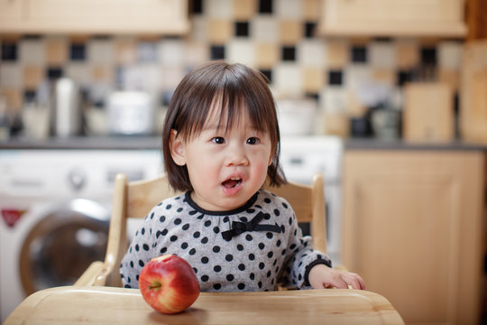 baby girl eat apple at home kitchen