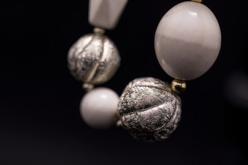 A part of a white bead necklace with gold and silver elements