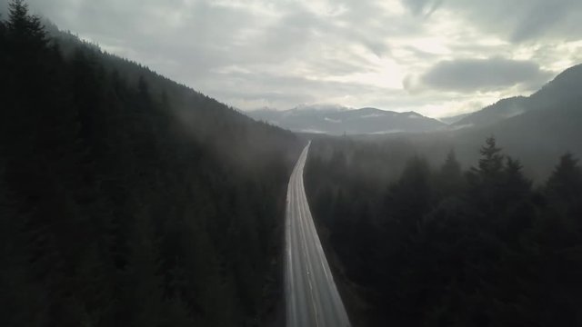Aerial 4k footage of a scenic road passing through a beautiful Canadian Landscape during a foggy morning. Taken on the Northern Vancouver Island, British Columbia, Canada.
