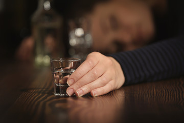 Unconscious drunk woman with glass of drink in bar, closeup. Alcoholism problem