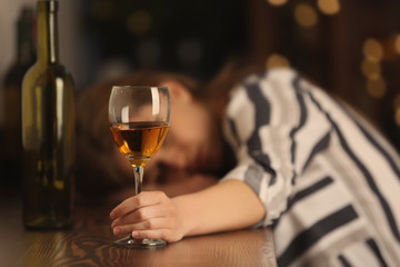 Unconscious drunk woman with glass of wine in bar. Alcoholism problem