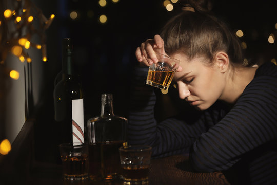 Young woman with glass of drink in bar. Alcoholism problem