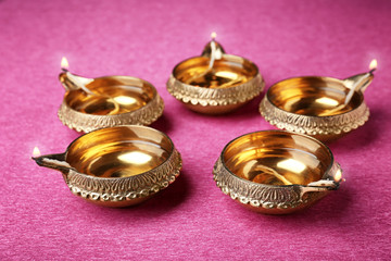 Diwali diyas or clay lamps on color background