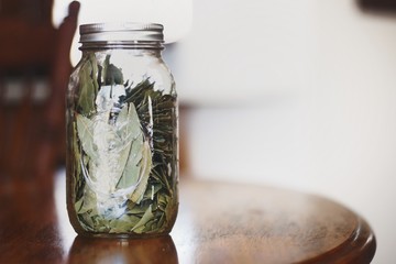 Mason jar with bay leaves against bright background - 195549805