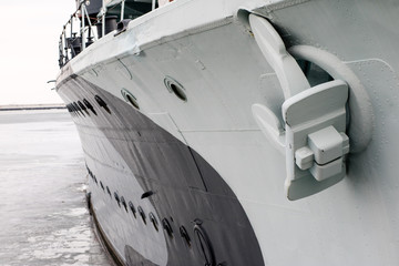 The anchor of a large warship standing in the port. Bow of a ship with an anchor on the side.