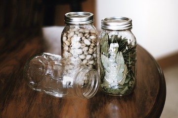 Mason jars with pistachios and bay leaves on dark, wooden table - 195550832