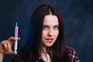 Obraz premium Young cute smiling woman with medical syringe studio shoot. Drugs addiction concept