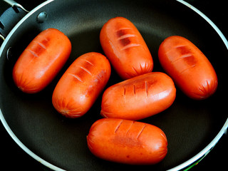 Roasted mini sausages. Mini sausages in a skillet with croutons.