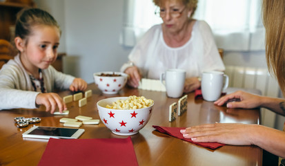 Grandmother, daughter and granddaughter playing domino in the living room