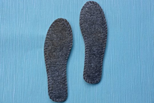 две серых стельки из войлока на синем столе