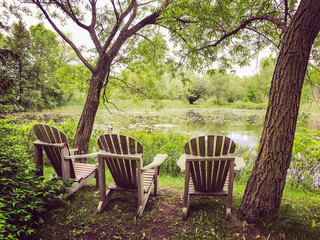 Wooden chairs near a pond in the summer park