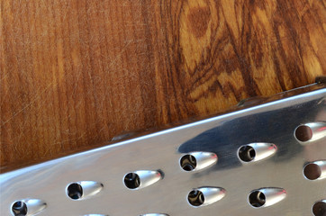 The chrome grater lies on the cutting board with a lot of scars from the ax and knife. Background...