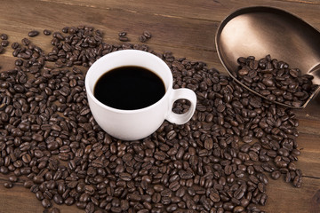 Cup of coffee and coffee beans on old wooden background.