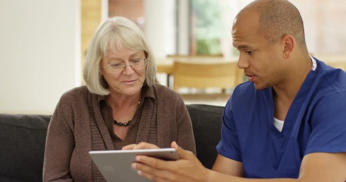 4k, Doctor showing a senior patient some information on a digital tablet in his office. Slow motion