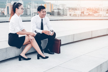 Asian businessman and businesswoman or Confident business partners sitting on staircase office...