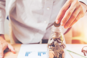 Handles coins placed on a pile of money on the table with light Sunset's business concept.