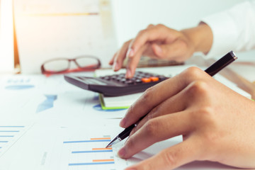 business people who use a calculator with financial concepts, spreadsheet data, business people use their fingers to compute calculations for 2018