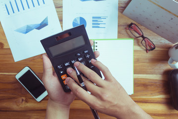 Top view of business people who use a calculator with financial concepts, spreadsheet data, business people use their fingers to compute calculations
