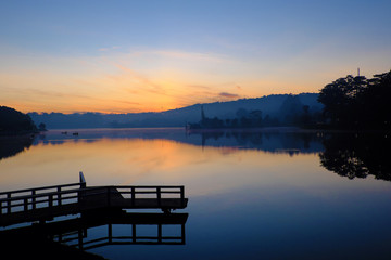 Fototapeta na wymiar small bridge reflect on lake at sunrise