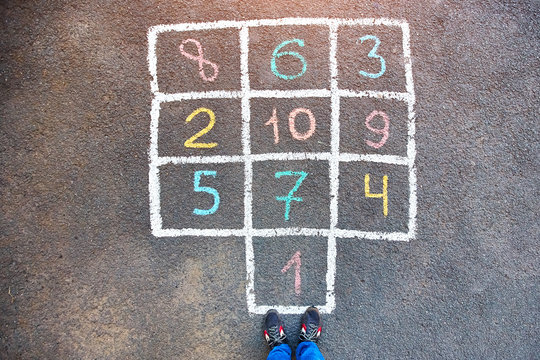 Closeup of hopscotch drawn with chalk on asphalt road. Children games and outdoor activities.