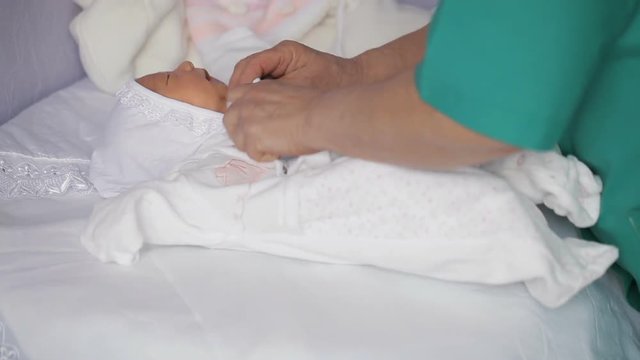 Dressing newborn girl in maternity hospital
