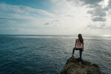 Fototapeta premium Woman standing on cliff and looks to ocean