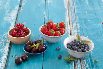 Many different kinds of berries on blue wood table