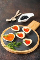 Tartlets with red caviar on a slate board. Valentine's day concept. Selective focus