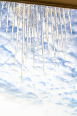 Row of Large Sparkling Icicles on Window Frame at Sky