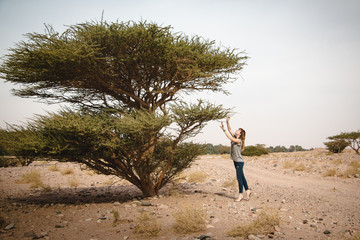 Pretty girl have fun on a tree in the desert