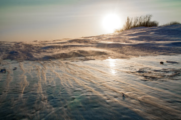 snowdrift on a frozen river during the sunset on a cold winter day