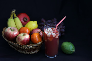 Dark Food - Chiaroscuro mixed fruit in wicker basket with fruit punch with dark background and copy space