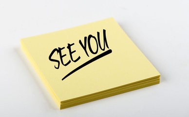 Concept of note with the words See you written on the yellow paper. Mockup.