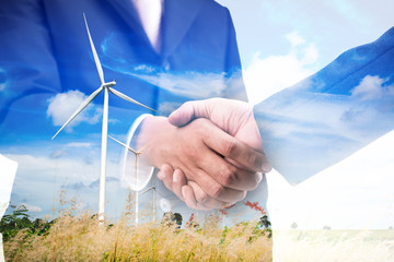 Double exposure of business handshake with wind turbine, green energy concept 