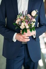 groom holding bouquet of roses, berries and eustoma