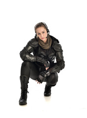 full length portrait of female  soldier wearing black  tactical armour, seated pose, isolated on white studio background.