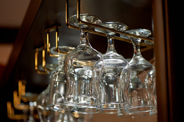 Wine glass glasses hang on the holders above the bar. The atmosphere of the evening pub, restaurant, cafe