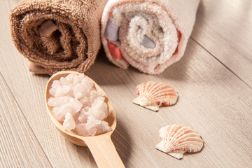 Wooden spoon with white sea salt for bathroom procedures with towels on the background