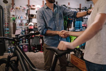 Fototapeta na wymiar Sports shop owner selling bicycle to customer