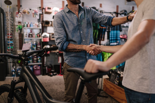 Sports shop owner selling bicycle to customer