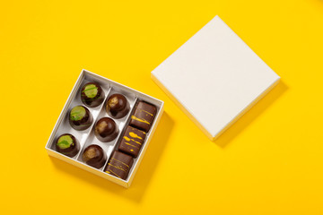 Assortment of luxury bonbons in box on bright yellow background