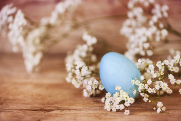 Fototapeta na wymiar blue easter egg and gypsophila (baby breath flower) on a rustic wooden background with copy space, vintage color filter
