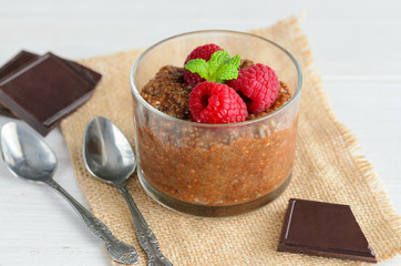 Delicious  Chia chocolate pudding with almond milk and raspberries in glass on wooden table. Raw  Vegan dessert background. Superfoods and healthy eating concept.