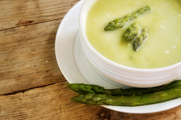 green asparagus soup in a bowl ona rustic wooden table, copy space, close up